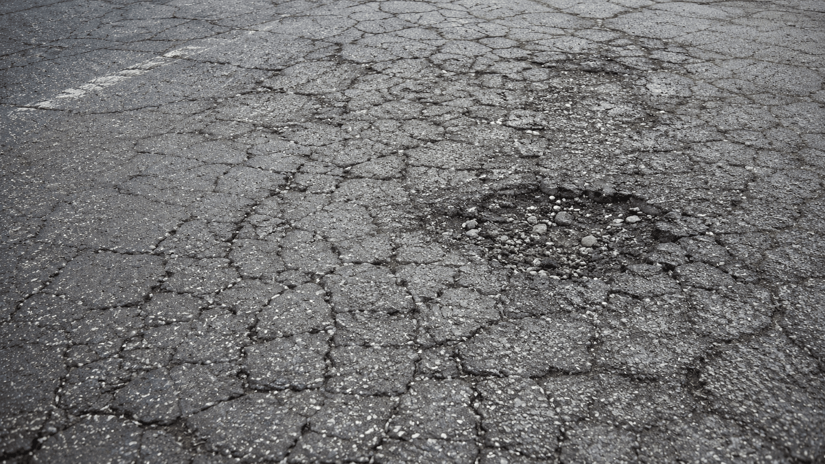 Cracked, aging commercial parking lot surface nearing the end of its life