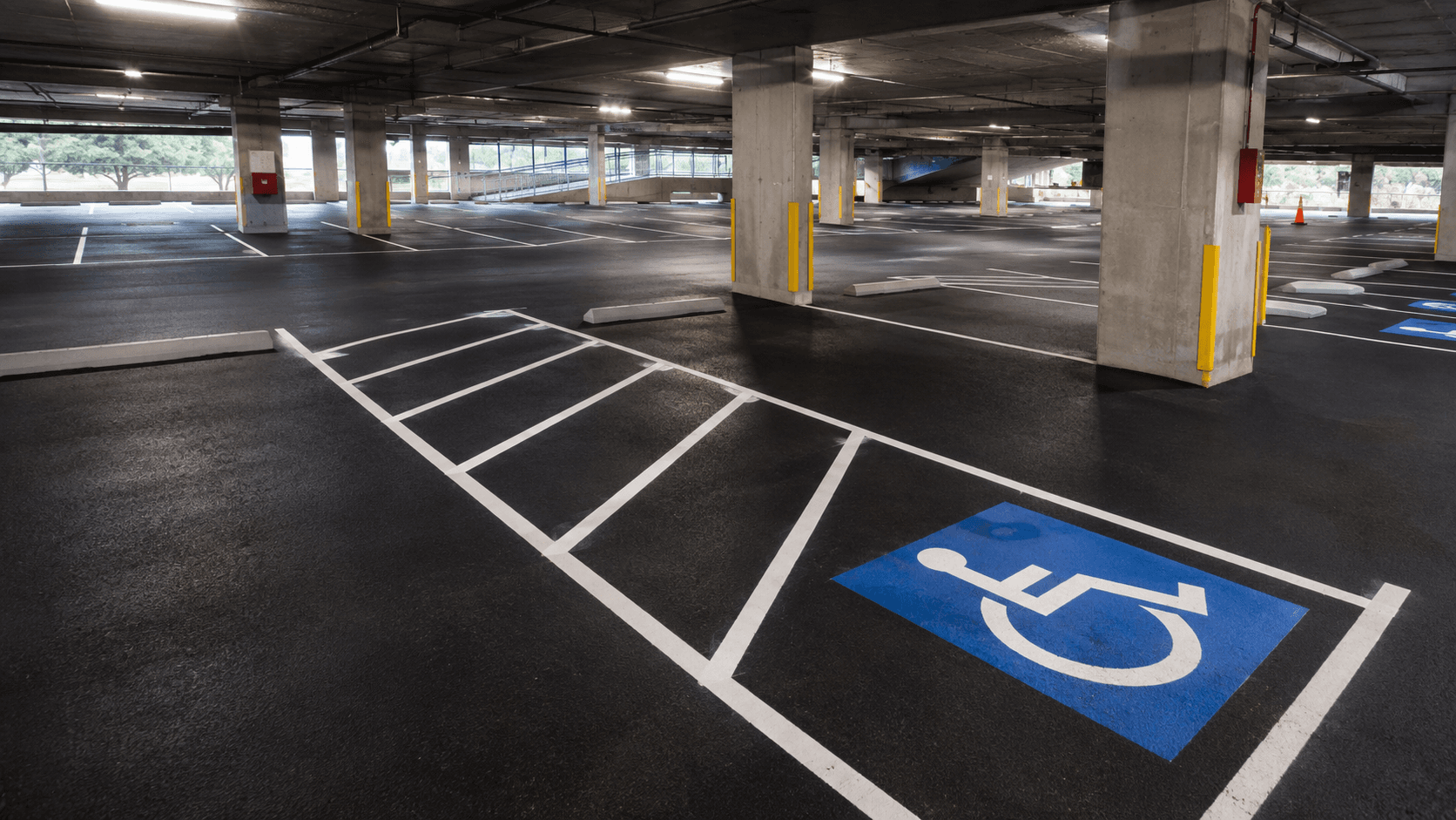 Freshly striped multi-level parking garage interior with reflective lines and ADA markings