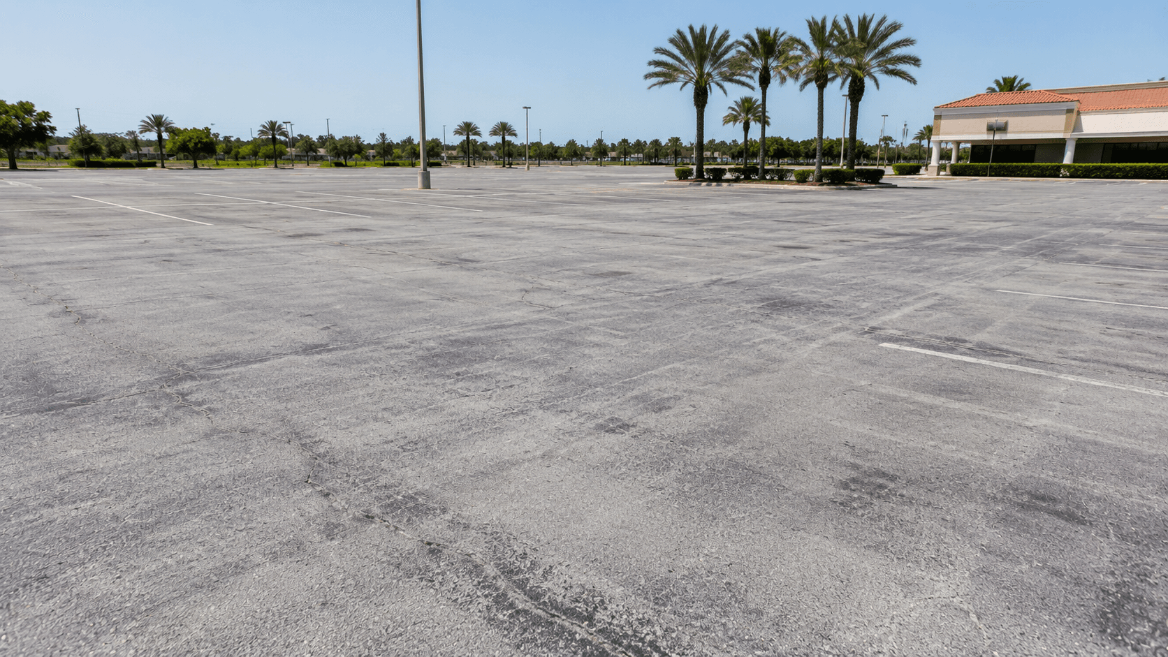 Sun-faded, oxidized commercial parking lot surface under intense summer heat
